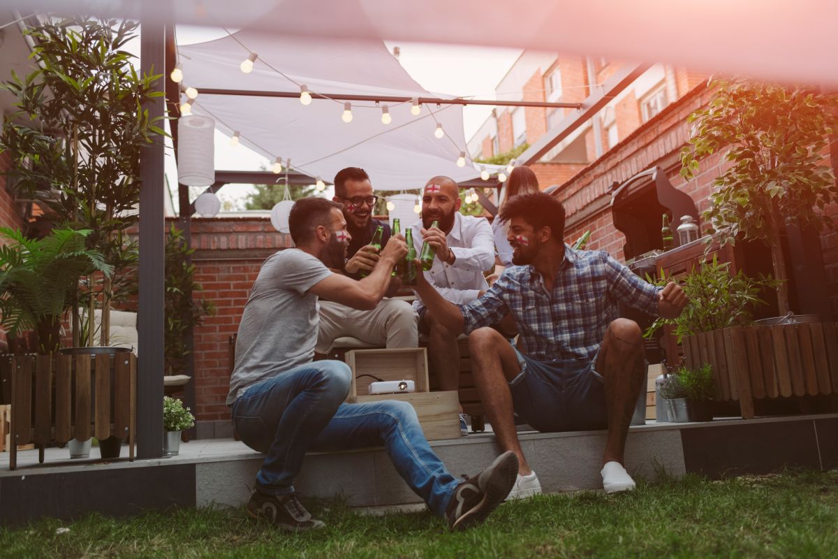 Friends Watching Soccer Game On Big Screen In Backyard