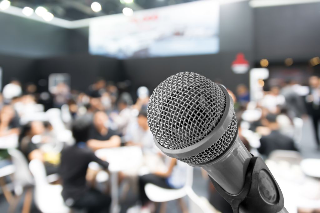Microphone with blurred photo of conference hall or seminar room with attendee background, Business meeting concept.