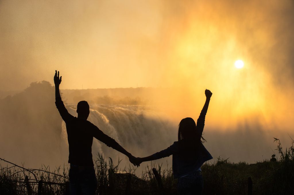 Early morning Silhouette of Couple at Victoria Falls Arms Raised
