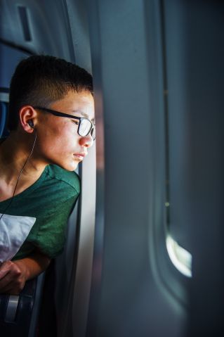 Teenage boy looking out of plane's window