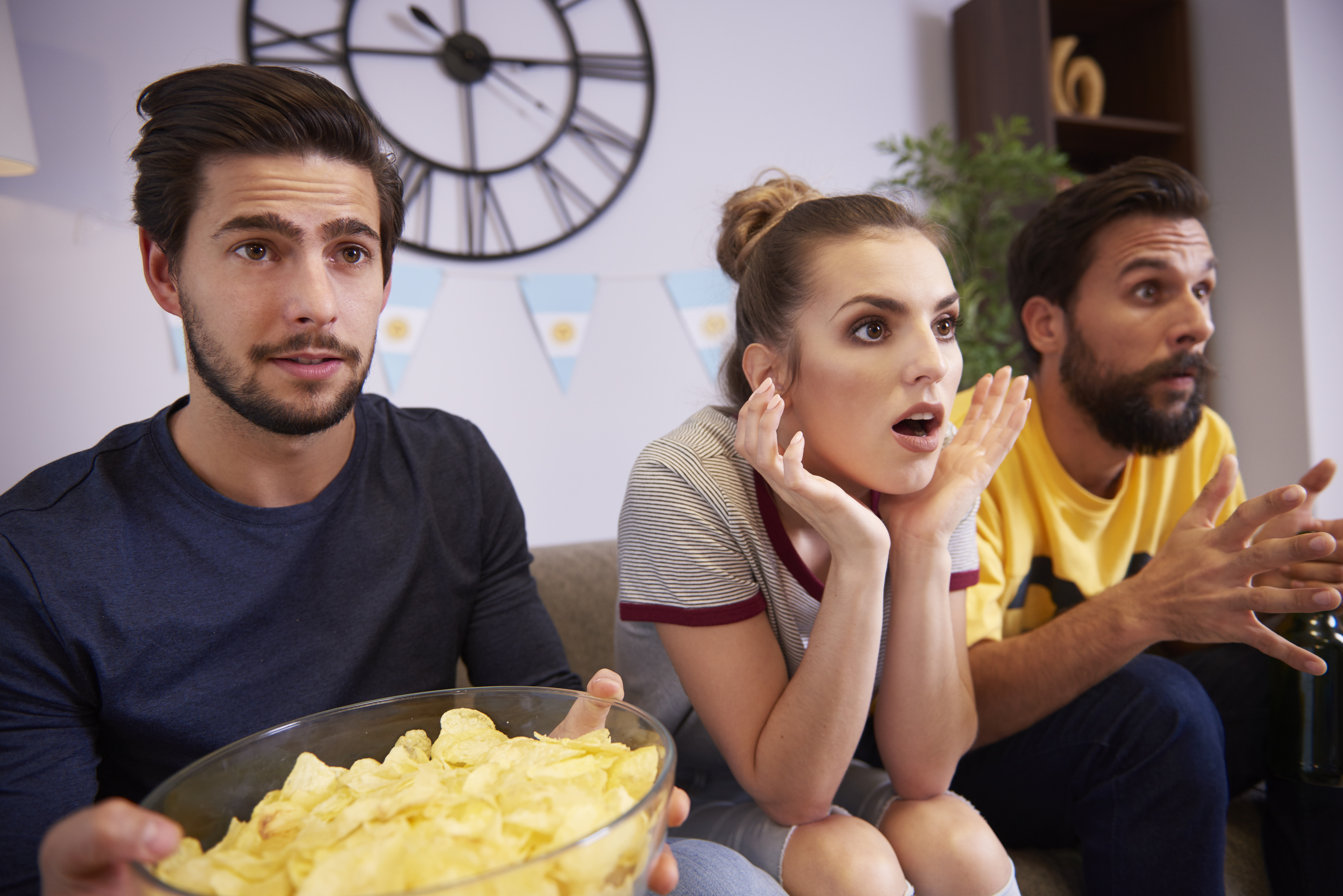 Excited friends sitting on the sofa watching Tv