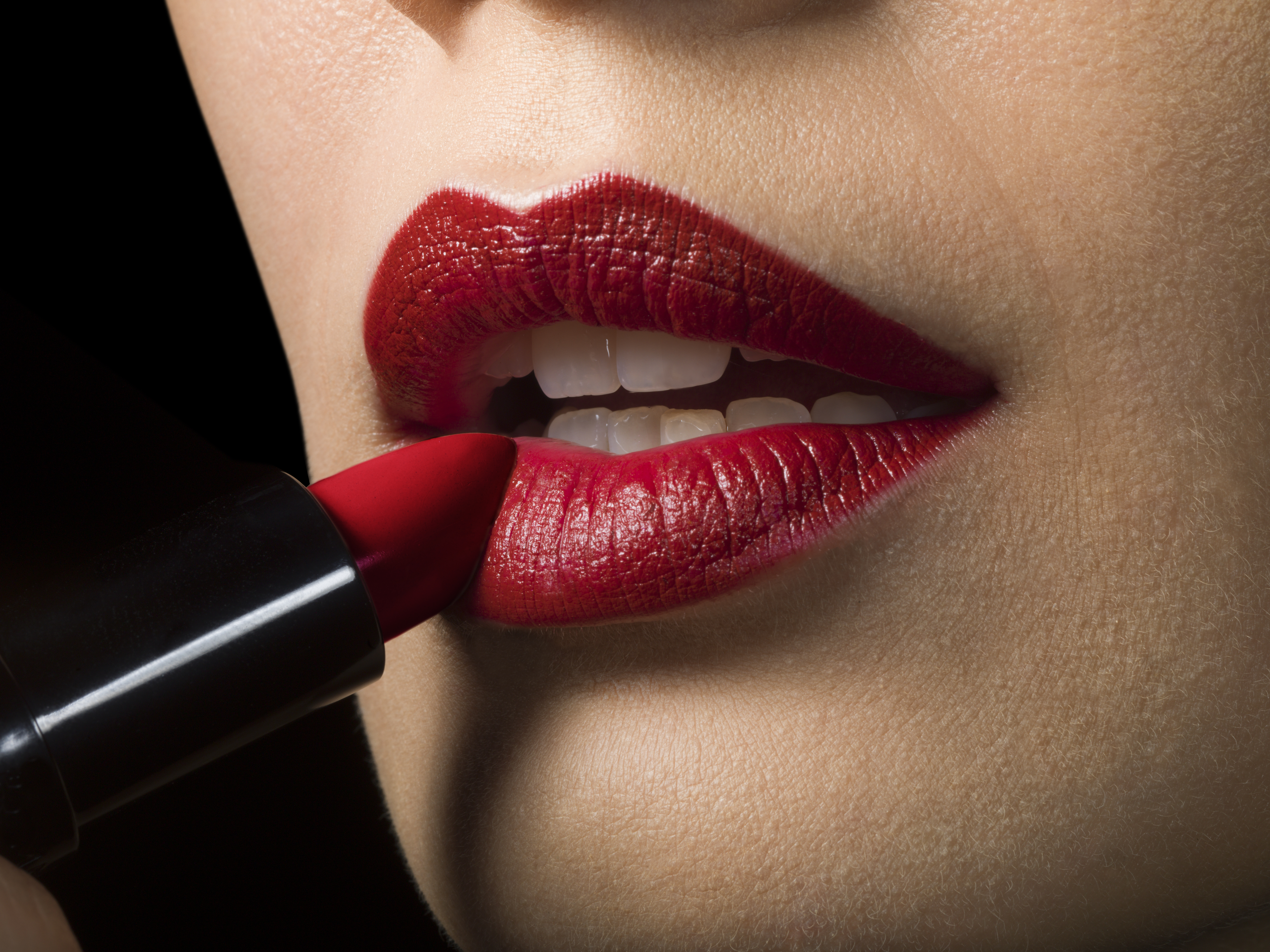 Female applying red lipstick, close up