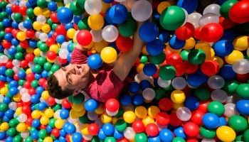 young man falling into a ball pool