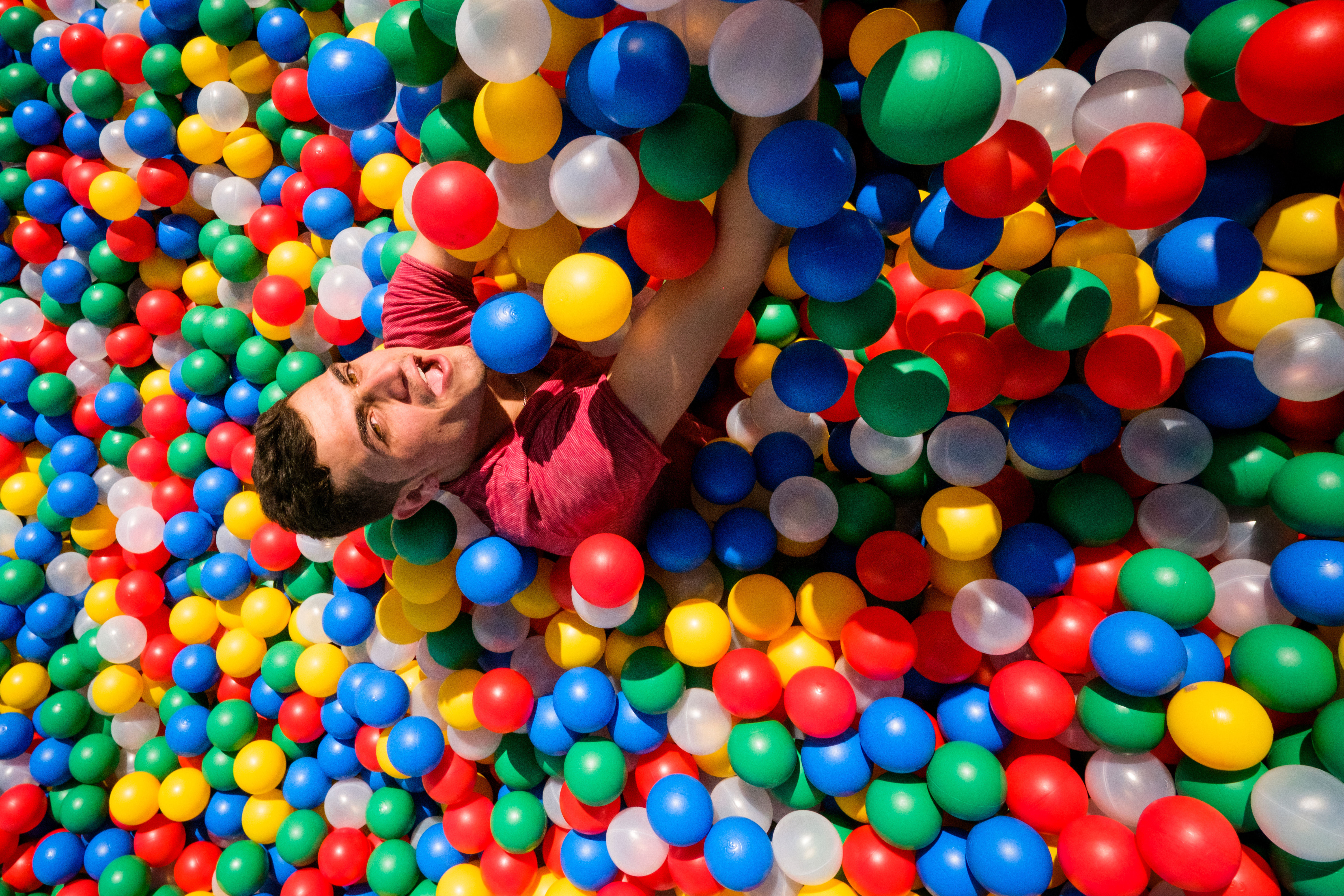 young man falling into a ball pool