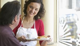Young waitress serving client in cafe, smiling