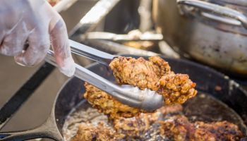 Close-up of tongs pulling out fried chicken from a cast iron pan at the Waverly Farmers Market in Baltimore, Maryland