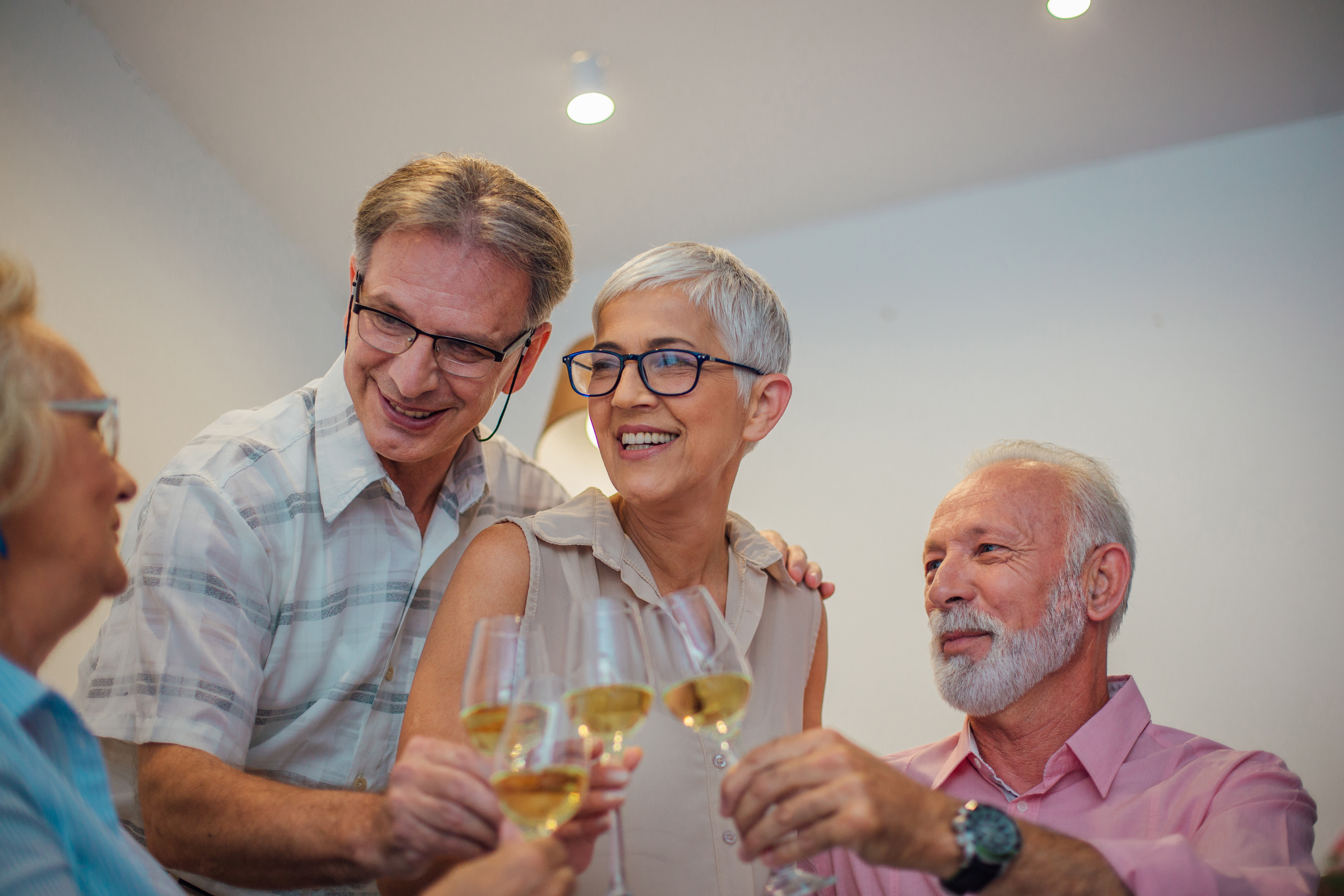 Senior couple hugging and having celebratory toast with friends