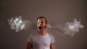 Screaming Man With Cotton Emitting From Ears Against Gray Background