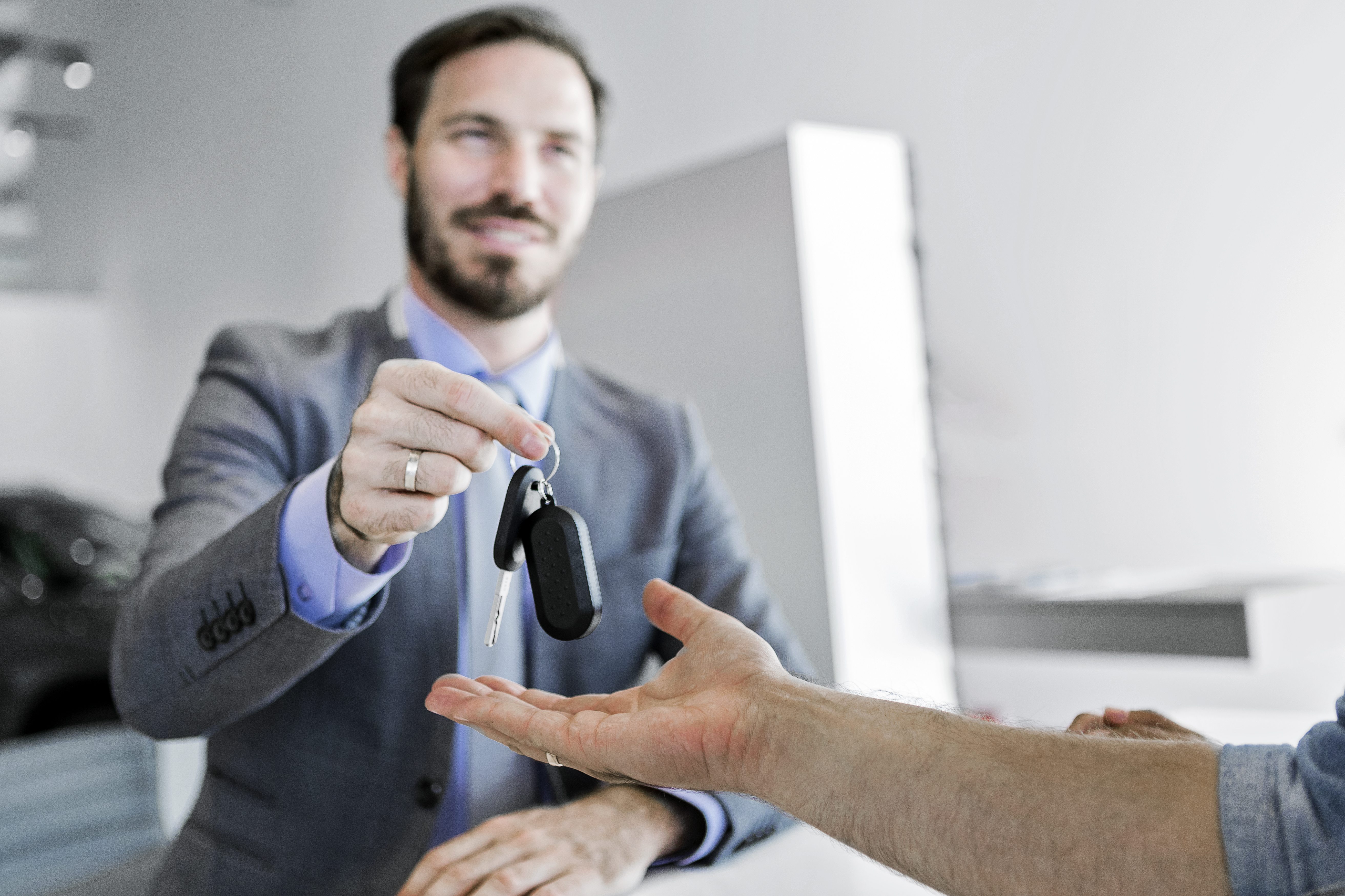 Car salesman making a sale in office delivering car key