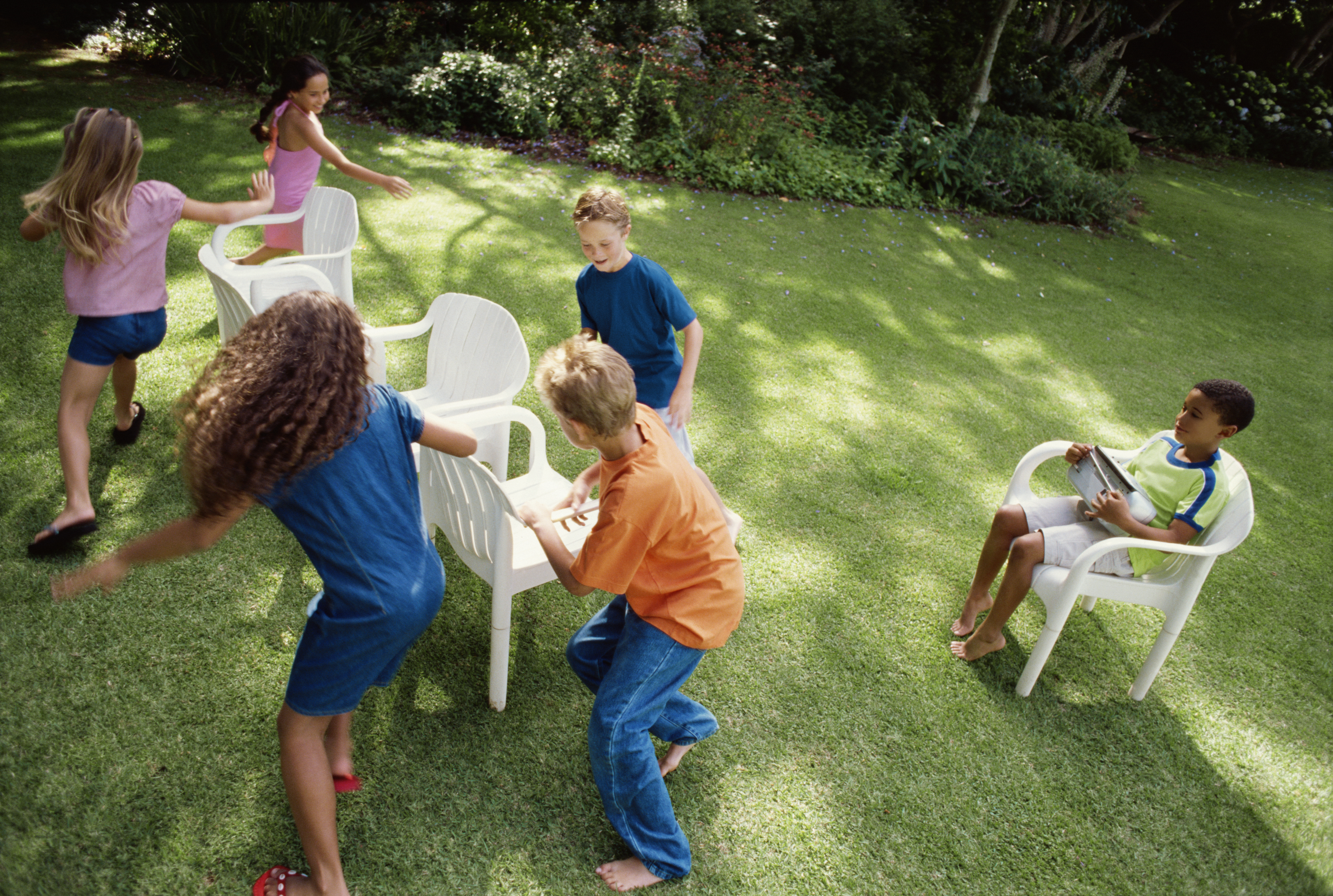Children playing 'musical chairs' in back yard