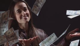 Portrait Of Young Woman Throwing Currency Against Black Background