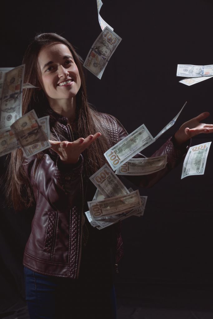 Portrait Of Young Woman Throwing Currency Against Black Background