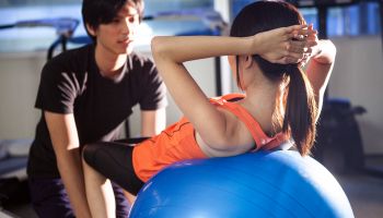Man and woman working out with exercise ball in gym.