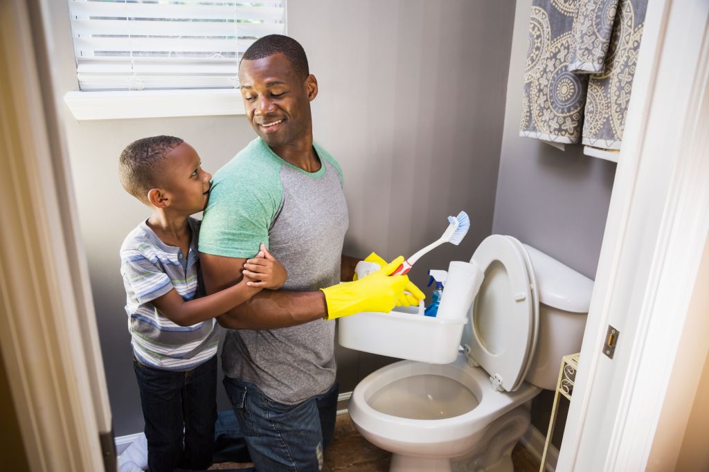 African American man with son, cleaning bathroom toilet