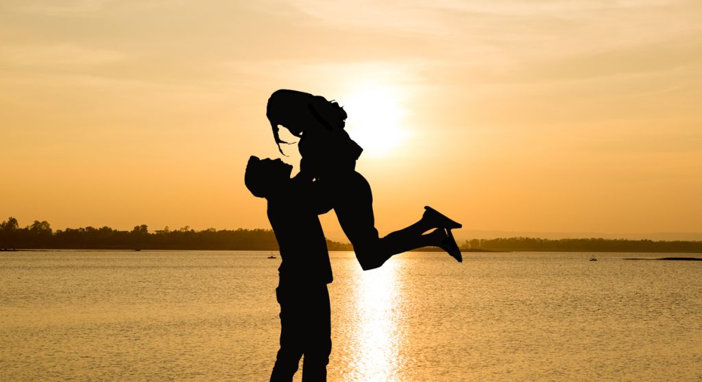Silhouette Man Lifting Woman By Lake During Sunset