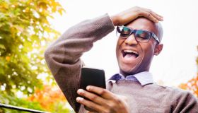 Mature man laughs out loud at story on mobile phone