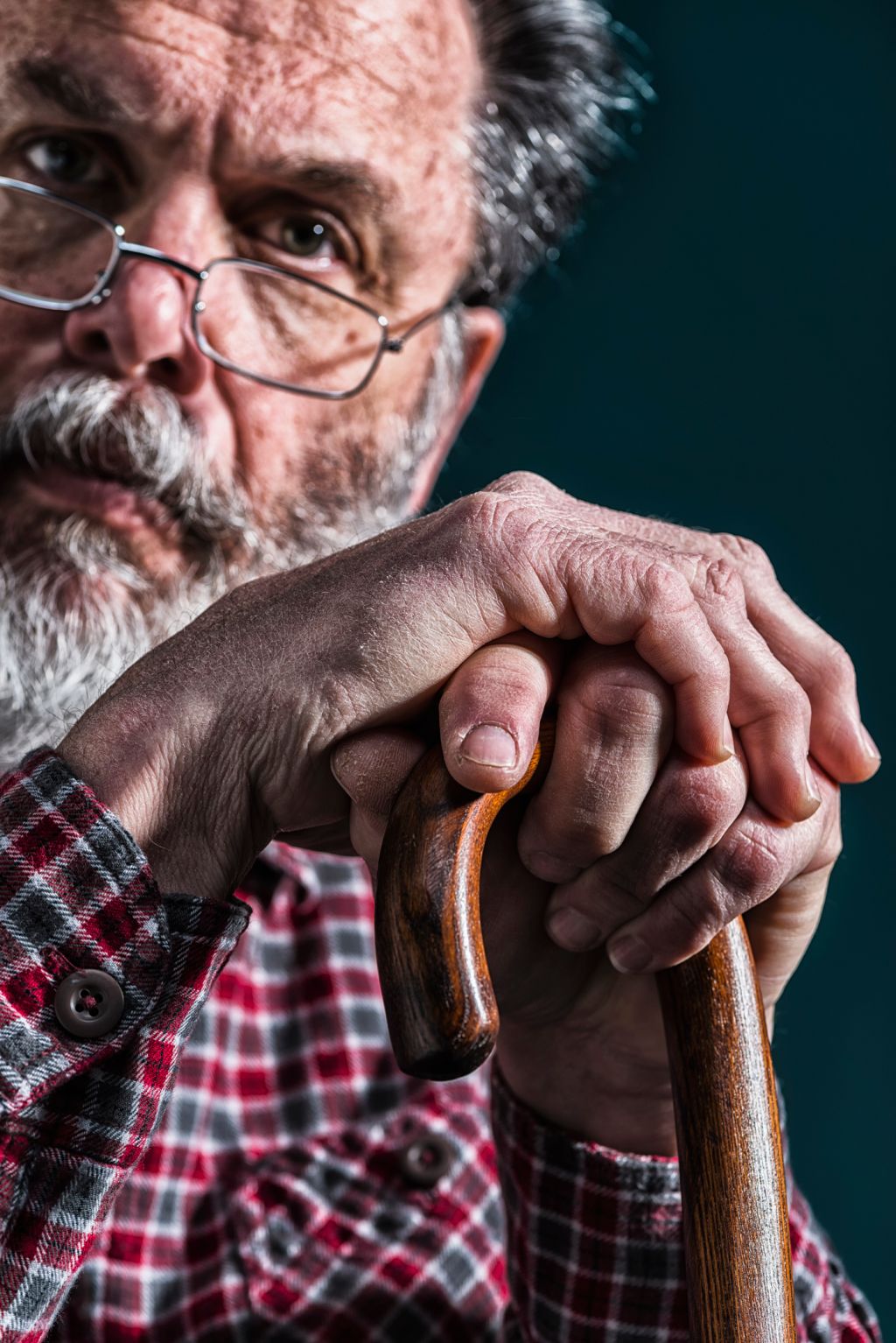 Close-up of old man's arthritic hands on cane