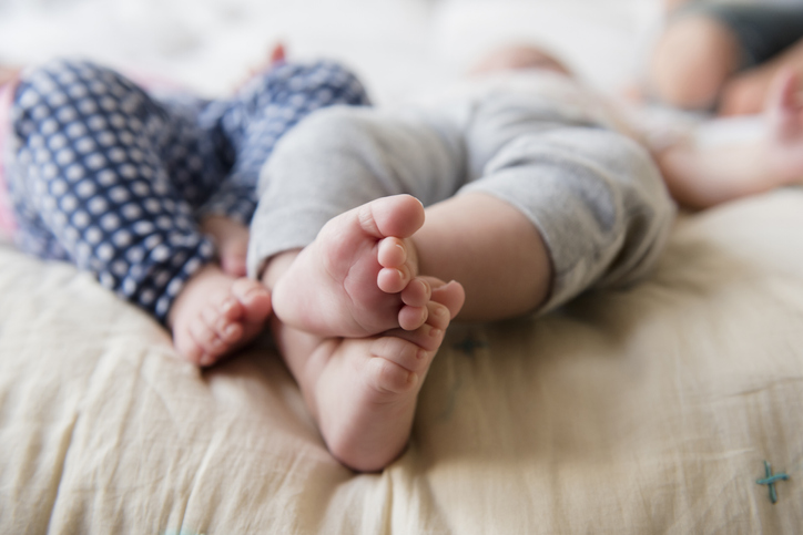 Feet of Caucasian twin baby girls laying on bed