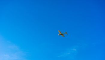 Small aircraft fly over blue sky
