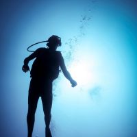 Silhouetted male scuba diver in ocean, Bali, Indonesia
