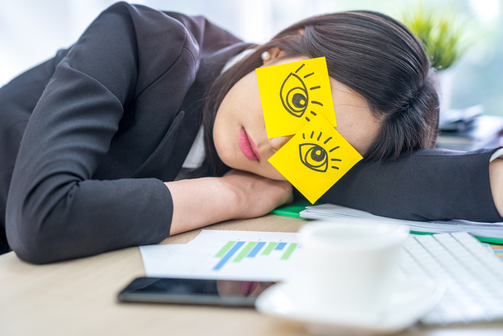 Lazy unproductive office wearing drawing funny eyes sticky notes on her glasses and sleepy on the office desk
