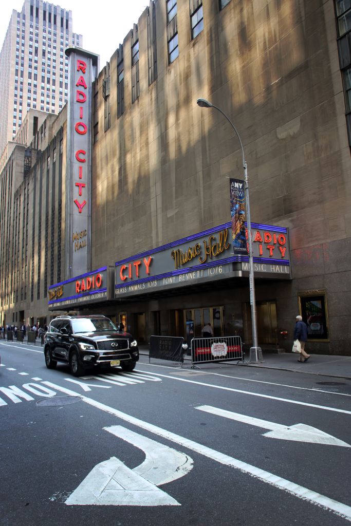 Black car driving by the Radio City Music Hall, Rockfeller Center, Midtown Manhattan, New York City