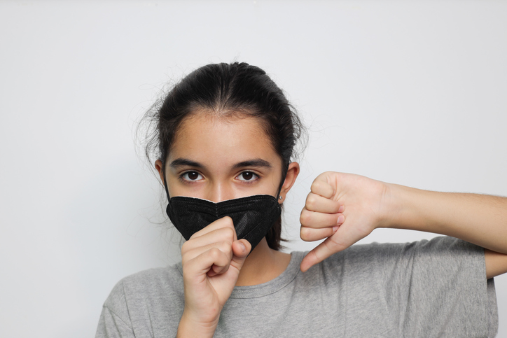 Portrait Of Girl Wearing Pollution Mask Coughing Against White Background