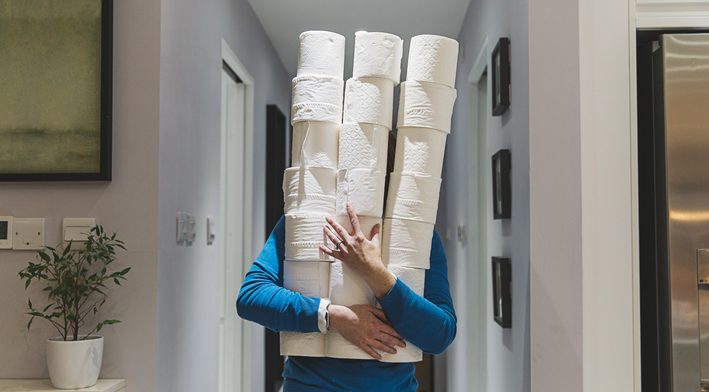 Person holding large piles of toilet rolls