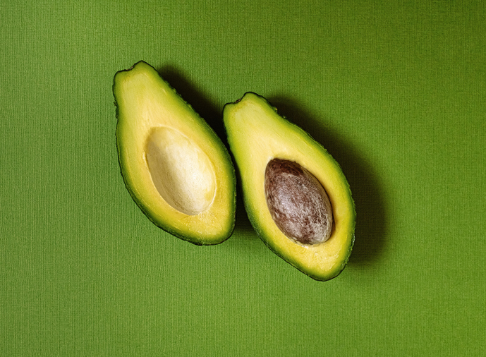 halved avocado on green background, healthy food, superfood, ketogenic diet, vegetarian, healthy fats, healthy lifestyle, wellbeing
