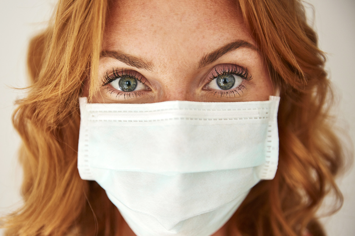 Portrait of red-haired woman wearing a face mask at home
