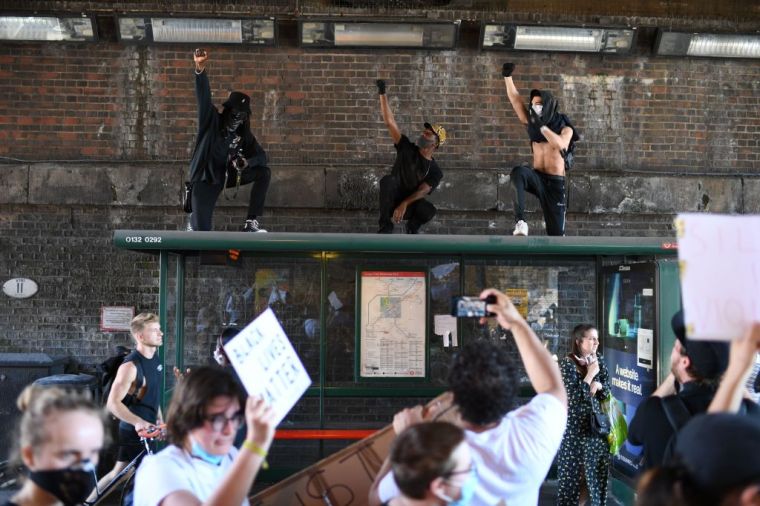 Demonstrators stand on top of a bus shelter as they march near the US Embassy in central London.