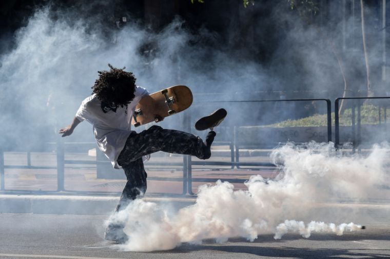 Demonstrator kicks a tear gas canister thrown by riot police in Sao Paolo, Brazil. People gathered to protest police brutality and President Jair Bolsonaro.
