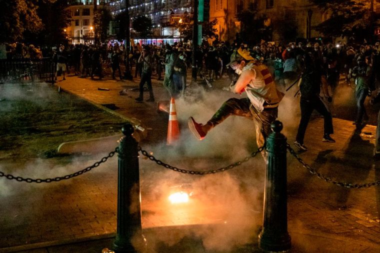 A protester kicks a tear gas canister back at police during a demonstration outside the White House.