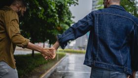 Gay couple holding hands while walking during a rainy day
