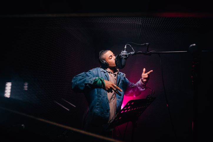 Young hipster African-American rapper recording songs in music recording studio