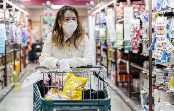 Safe shopping practice during a viral pandemic outbreak. A young girl wearing a protective mask and gloves in a grocery store.
