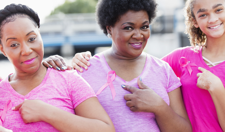 Three women wearing breast cancer awareness ribbons