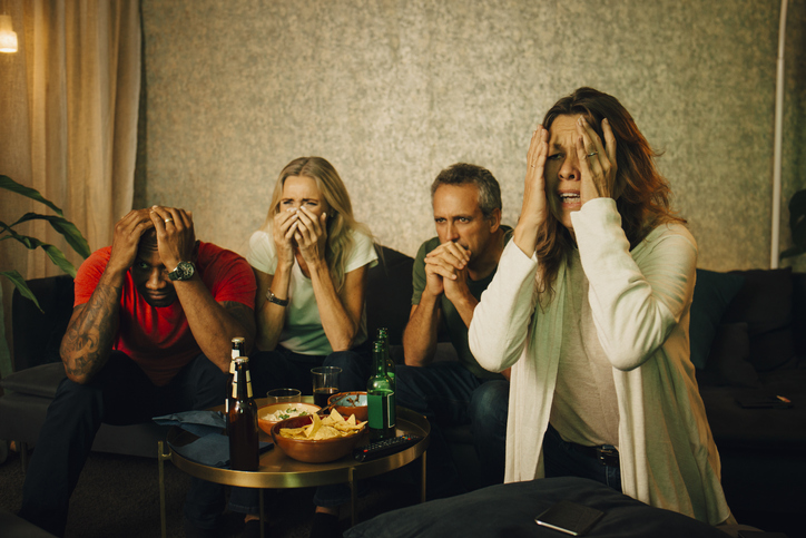 Disappointed heterosexual couples watching sports at night