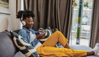 A young African-American woman is relaxing at home and using mobile phone