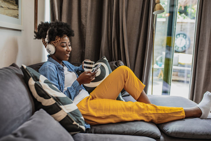 A young African-American woman is relaxing at home and using mobile phone