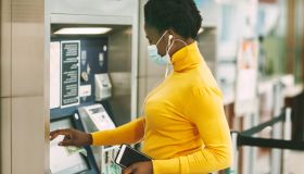 Dubai, Uae, November 2020 African Woman Wearing A Protective Mask Withdraws Money From A Bank Card