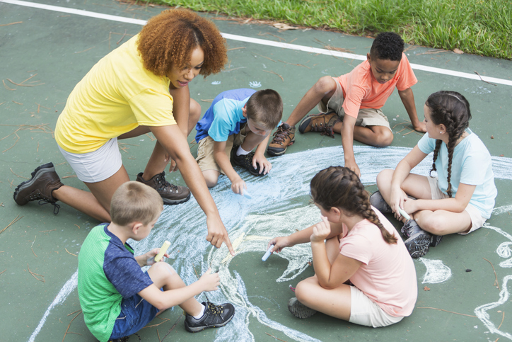 Camp counselor with children, chalk drawing of earth