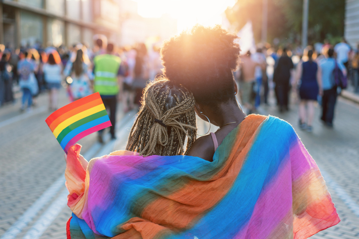 Young female couple hugging with rainbow scarf at the pride event