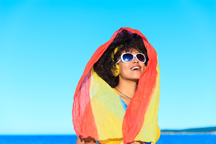 African woman in yellow outfit listen music on the beach