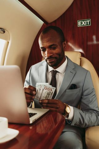 Businessman counting currency while traveling in private jet