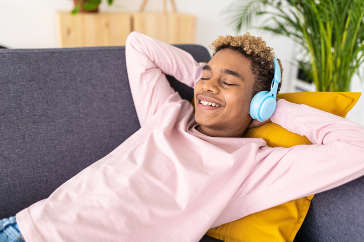 Un adolescent qui aime écouter de la musique tout en se relaxant sur un canapé à la maison.
