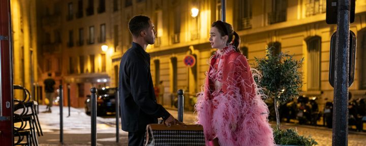 Emily In Paris production still from Season 3 showing Lucien Laviscount as Alfie having a serious chat with Lily Collins as Emily while holding his luggage