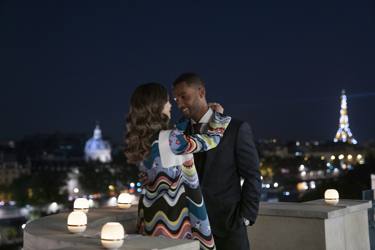 Emily In Paris production stills featuring Lucien Laviscount as Alfie and Lily Collins as Emily kissing