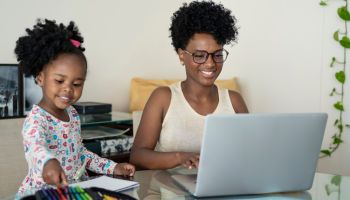 Mother working at home with daughter studying