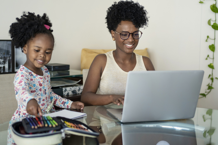 Mother working at home with daughter studying